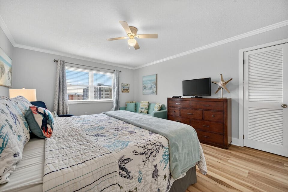 Cozy king bedroom w/ soft light, dresser storage & relaxed beachy decor.