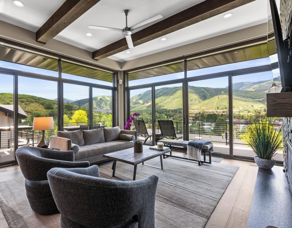 The living room has a wall of windows with views of Deer Valley Resort and Park City Mountain Resort including the Canyons.