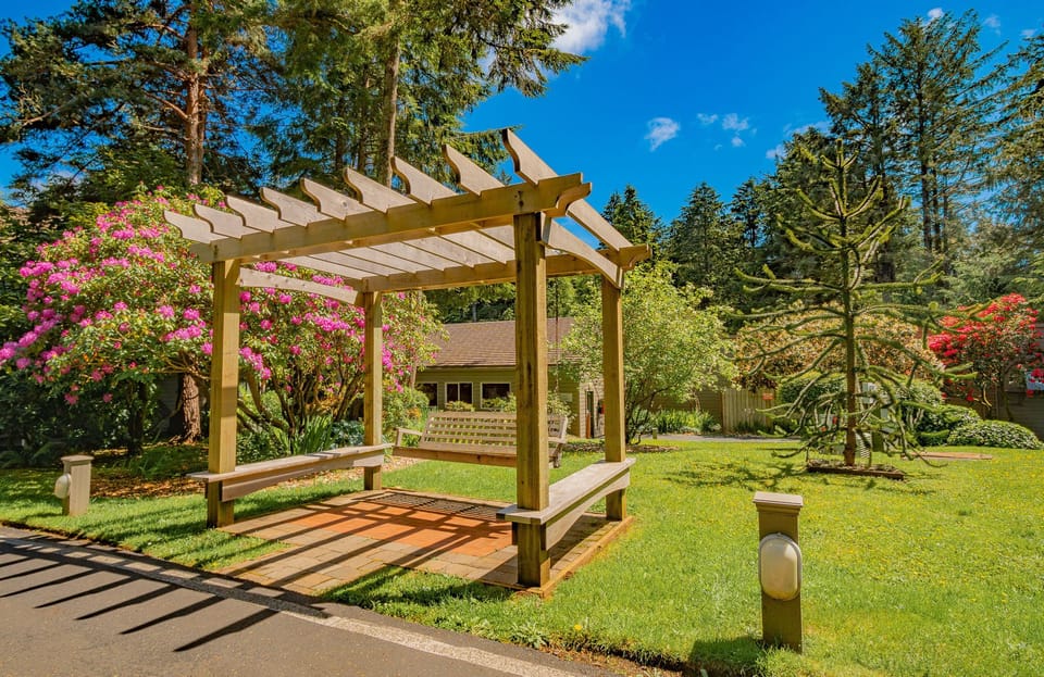 Relax in the inviting garden area featuring a charming pergola surrounded by vibrant flowers, perfect for enjoying the fresh coastal air.
