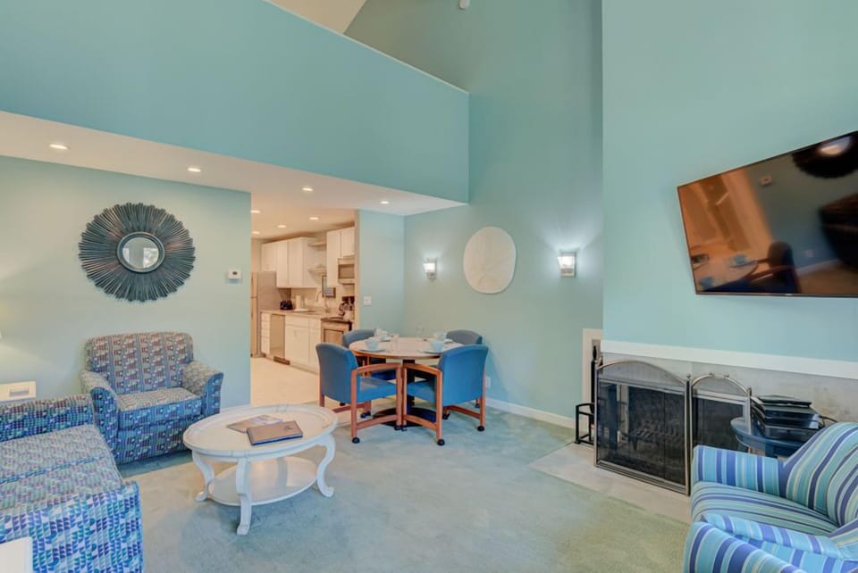 This inviting living area showcases a loft-style layout with stylish seating, a dining area, a full kitchen, and a charming fireplace.