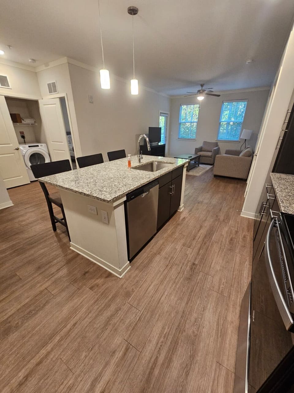 Spacious open layout combining kitchen and living room, featuring granite countertops and modern furnishings.