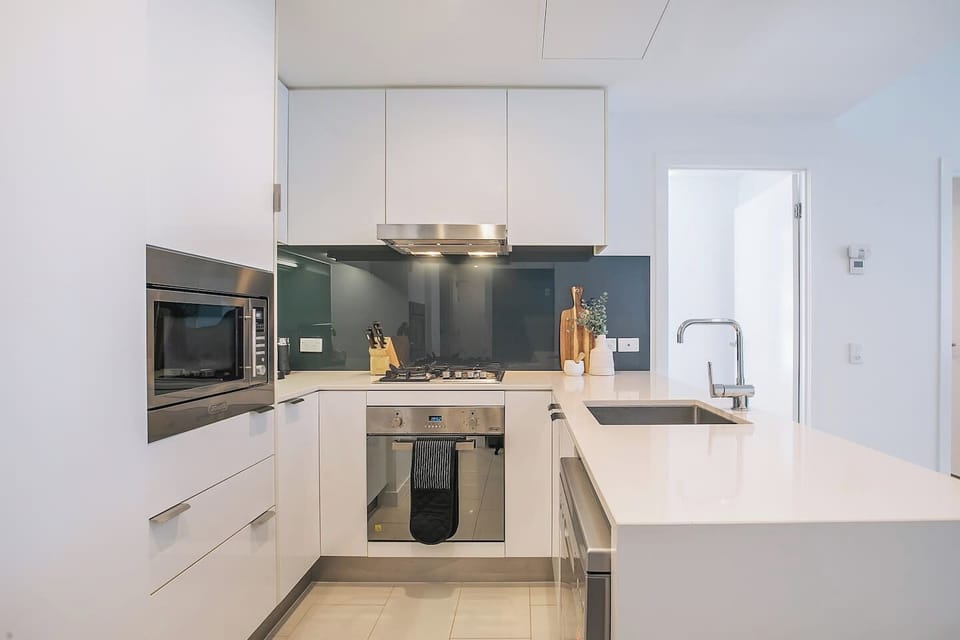 Prepare meals with ease in the full-sized kitchen featuring stone benchtops, sleek cabinetry, a gas cooktop, oven, microwave, and Nespresso machine.