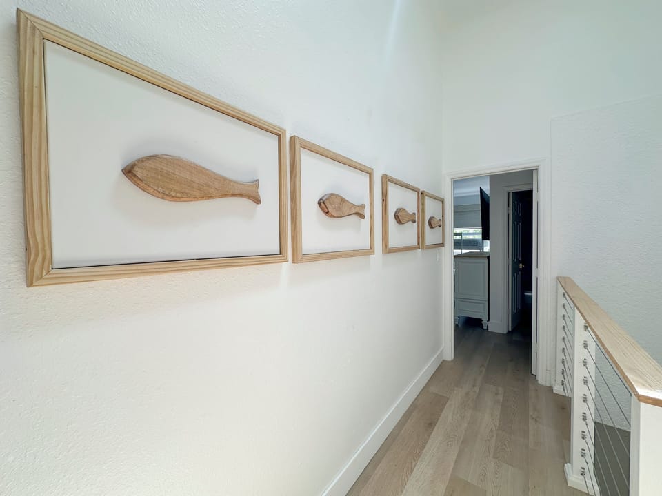 Hallway featuring curated coastal fish artwork.