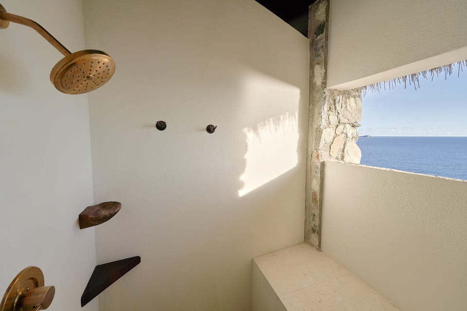 Private outdoor shower with natural stone wall and sparkling sea views.