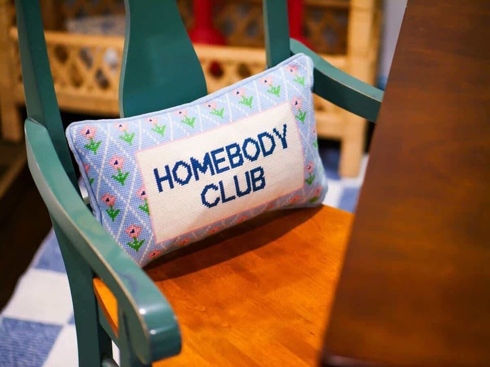 Creative nook featuring a “homebody club” sign & cozy decor