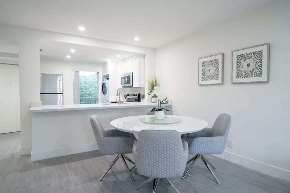 Dining area with round table, soft chairs, and kitchen view