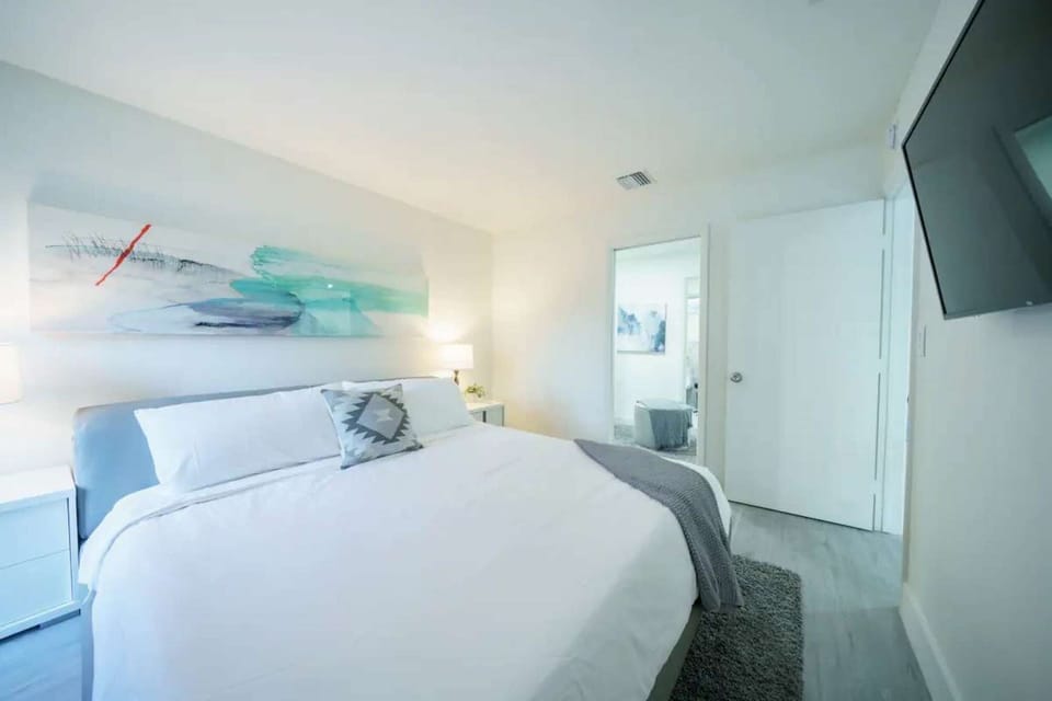 Bright bedroom with king bed, wall art, rug, and wall TV