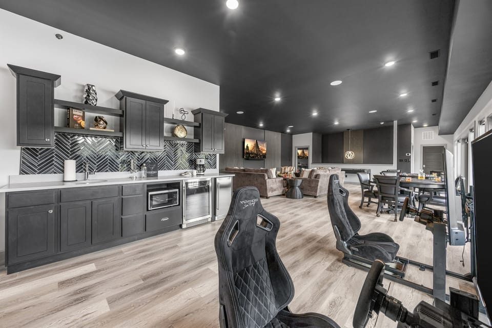 Enjoy a sleek, modern entertainment space featuring a fully equipped kitchenette, comfortable seating area, and multiple gaming setups. Perfect for relaxing, socializing, and enjoying your favorite games in a stylish, open-concept environment.