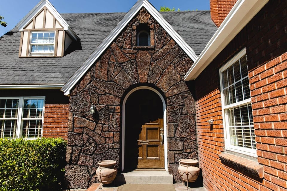 Arched stone entry and classic wood door offer a warm Tudor welcome