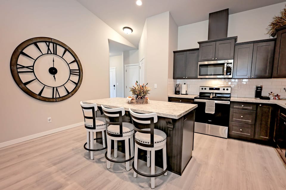 Modern kitchen with granite island, bar seating, and huge decorative wall clock.
