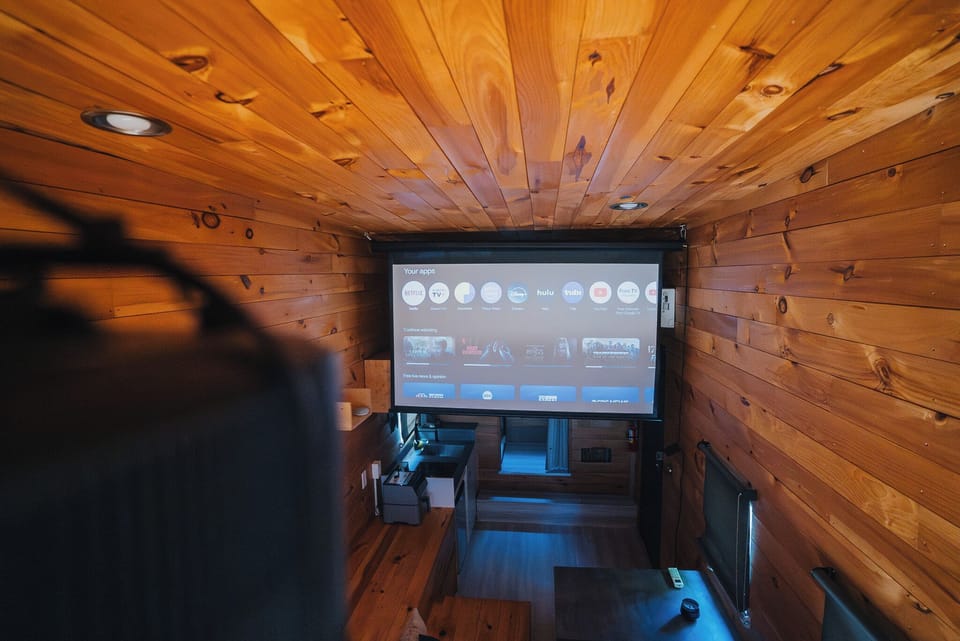 Cozy wood-lined tiny theater with projector and streaming apps