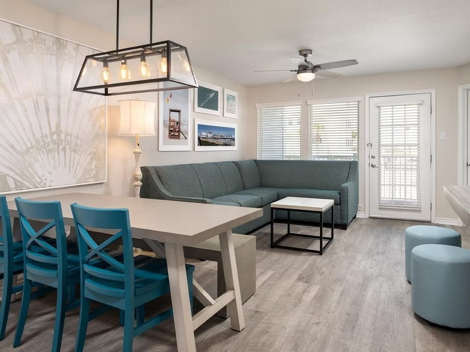Share meals and laughter beside sunlit seating and coastal artwork.