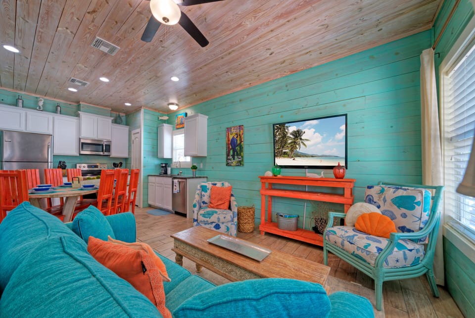 Gather in the living room, complete with two sofa chairs, a sleeper sofa, and a flat-screen TV.