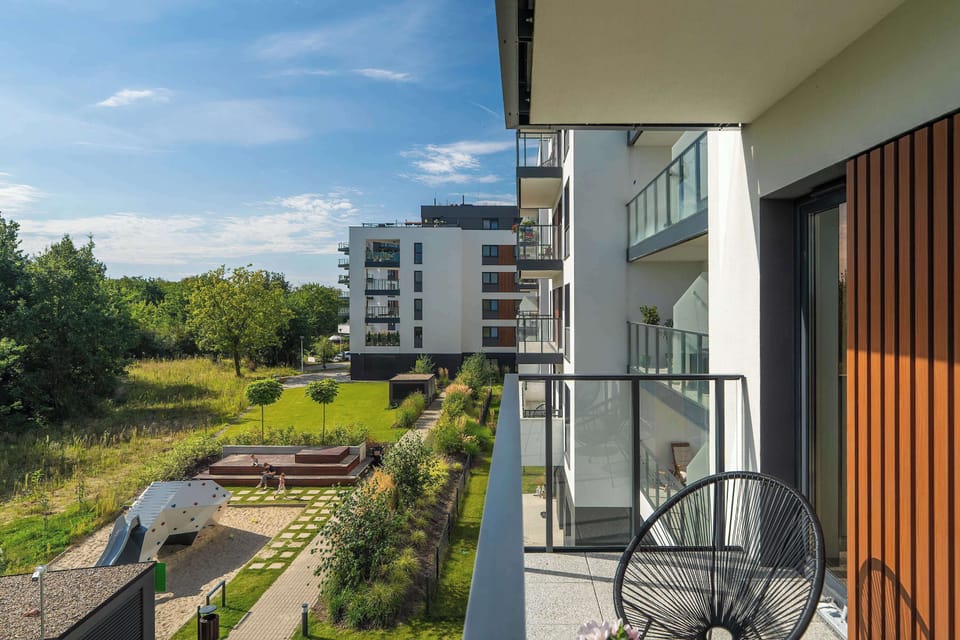 A balcony overlooking greenery and nearby buildings is the perfect spot to enjoy nature within an urban setting.