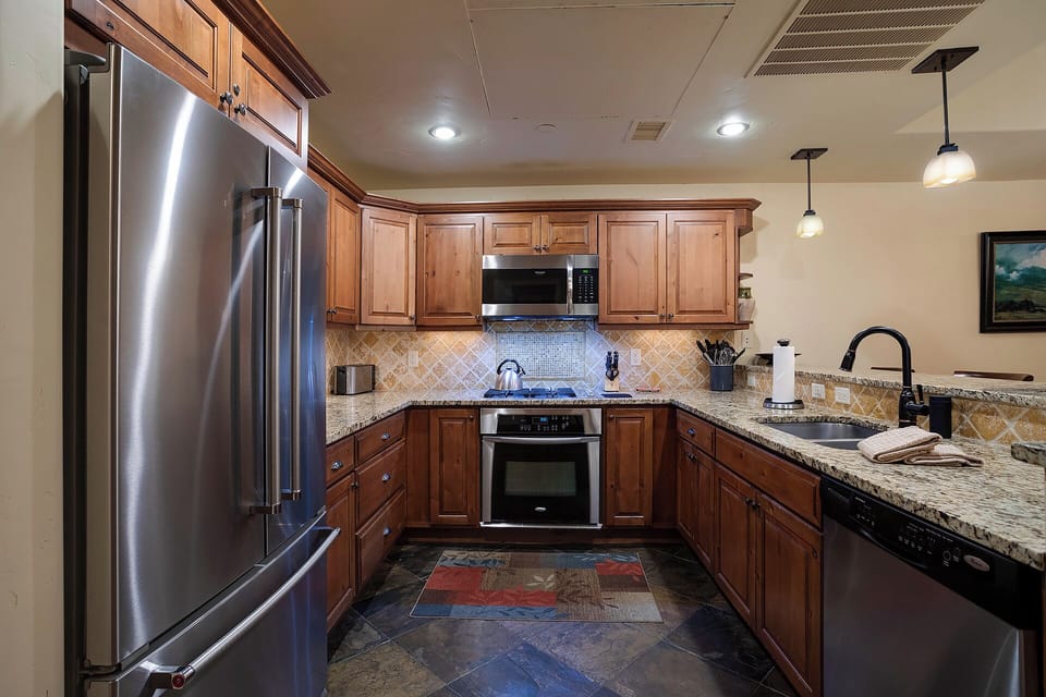 Your gourmet kitchen awaits with granite counters, stainless steel appliances, and warm wood cabinets perfect for creating memorable meals.