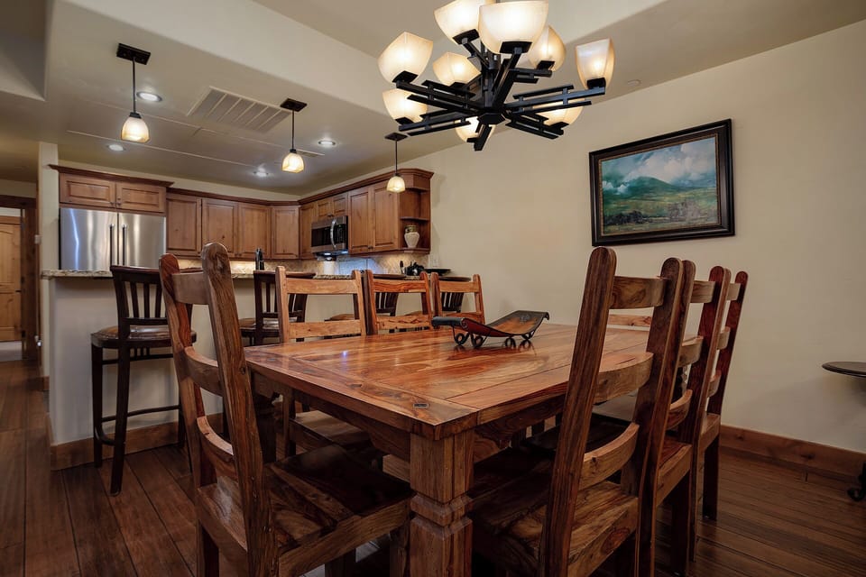 Gather around this stunning handcrafted dining table where your group can share memorable meals under elegant lighting.