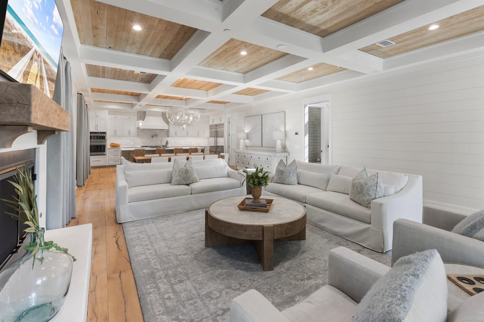 Sink into plush seating beneath stunning coffered ceilings where natural light streams through, connecting your elegant living space to the gourmet kitchen.