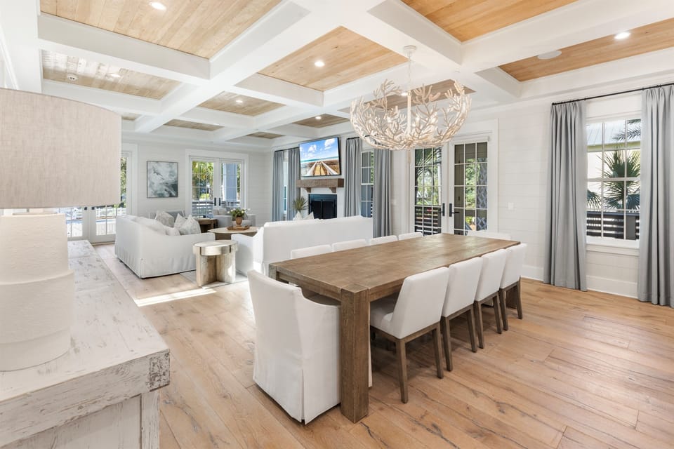 Gather around the stunning wooden dining table in this bright, open-concept living space with soaring coffered ceilings and elegant furnishings.