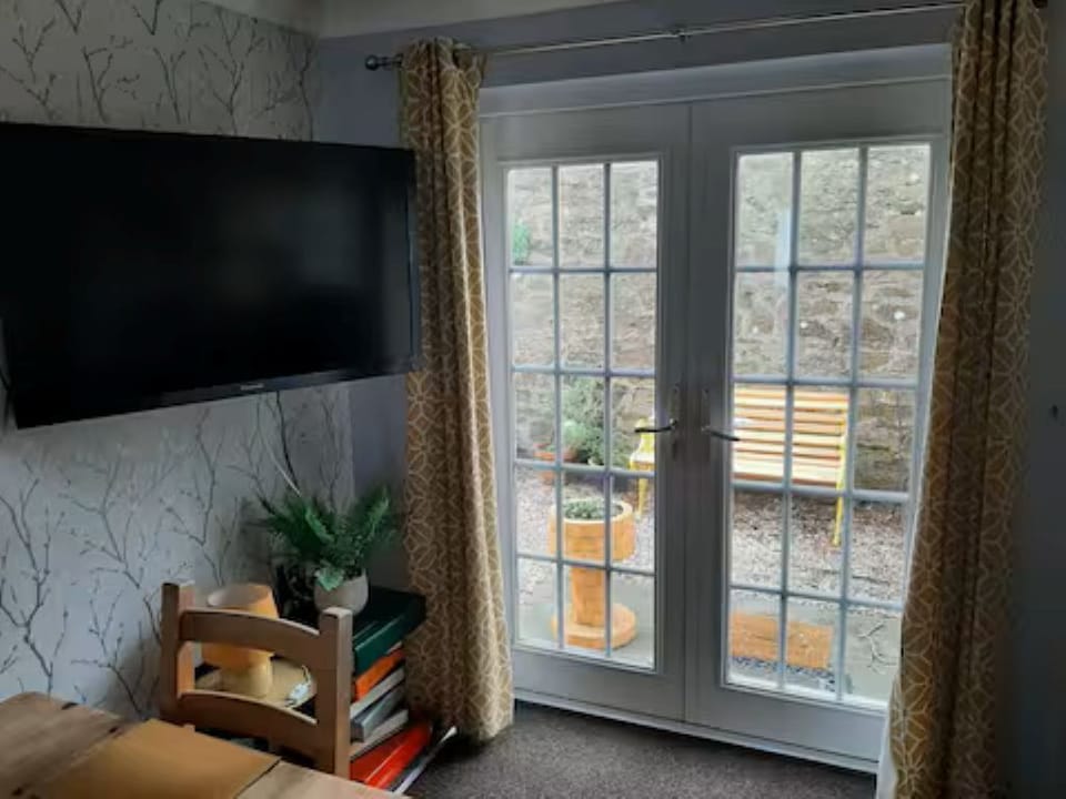 Living Room With TV, Sofa Bed & Black Out Blinds Leading To Courtyard Garden.