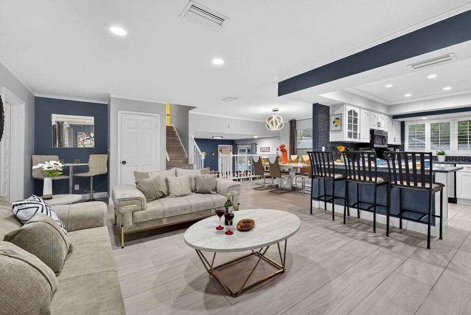 Open concept living room with sofa, loveseat, bar stools and dining table.