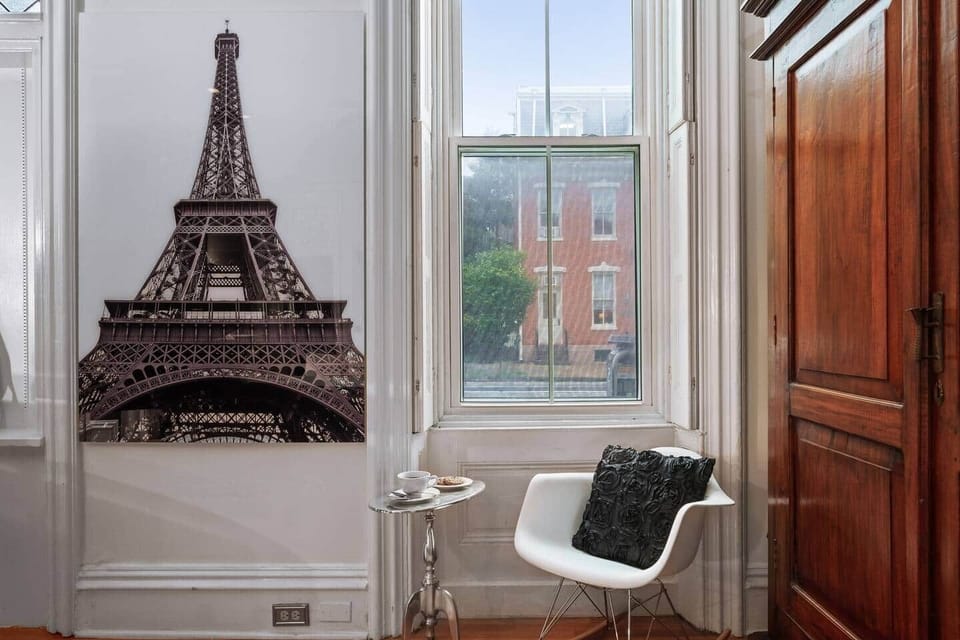 Charming reading nook with Parisian flair, featuring an Eiffel Tower wall art and elegant decor.