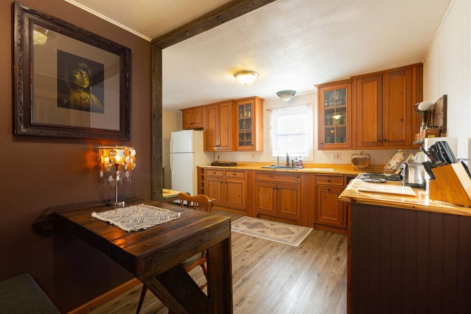 Kitchen Features reclaimed pine wood cabinetry and handmade pine countertops, combining rustic charm with functionality. Fully equipped with a sink, refrigerator, stove, coffee maker, olive oil, salt, pepper, silverware, cookware, dishes, and wine glasses