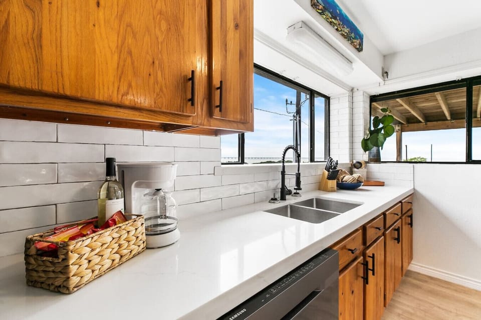 - Updated kitchen with quartz countertops and double sink - White subway backsplash, wood cabinetry and water views - Bright coastal kitchen with modern finishes