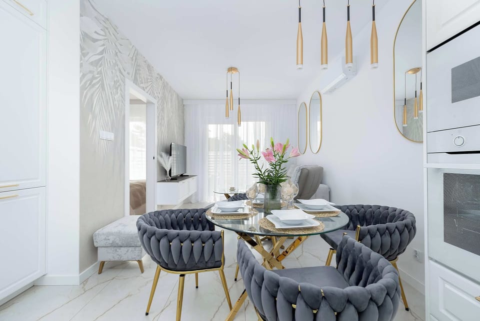 A modern dining space with a round table and upholstered chairs. A flower arrangement brings freshness to the interior.