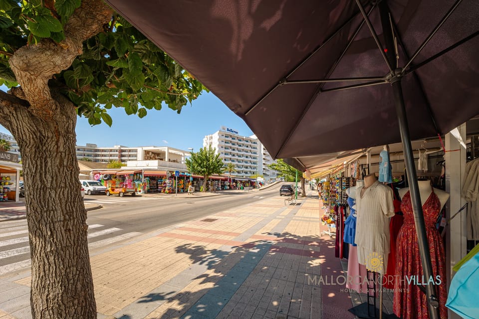 Commercial area with shops and a pedestrian walkway near the holiday rental apartment in Mallorca.