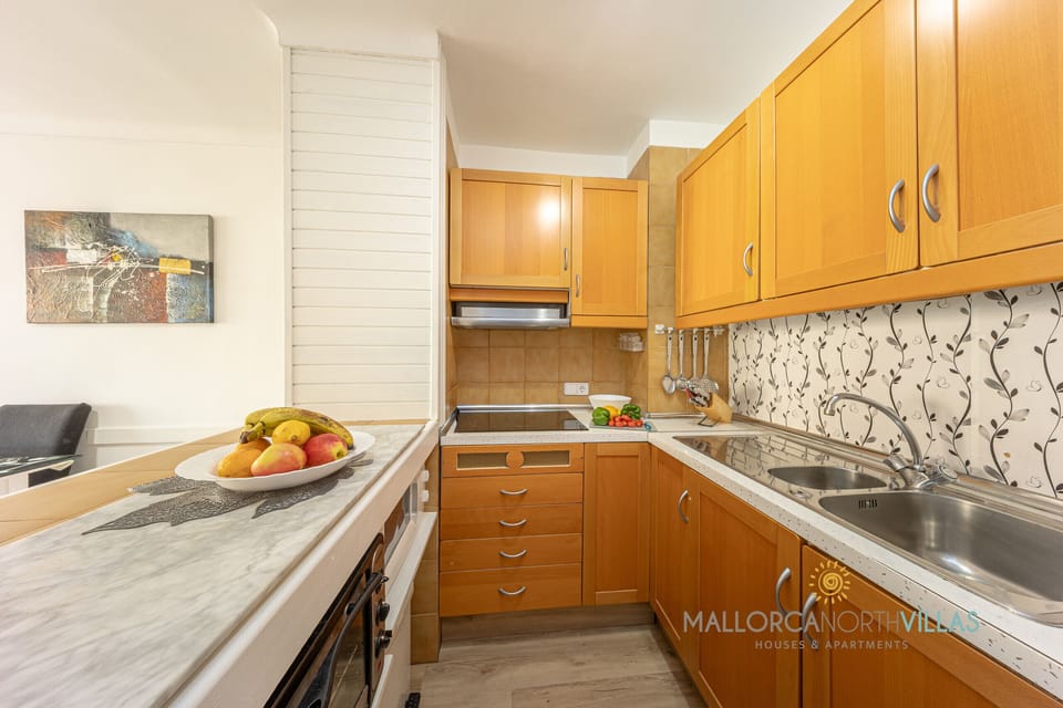 Equipped kitchen with wooden cabinets, ceramic hob and spacious countertop.
