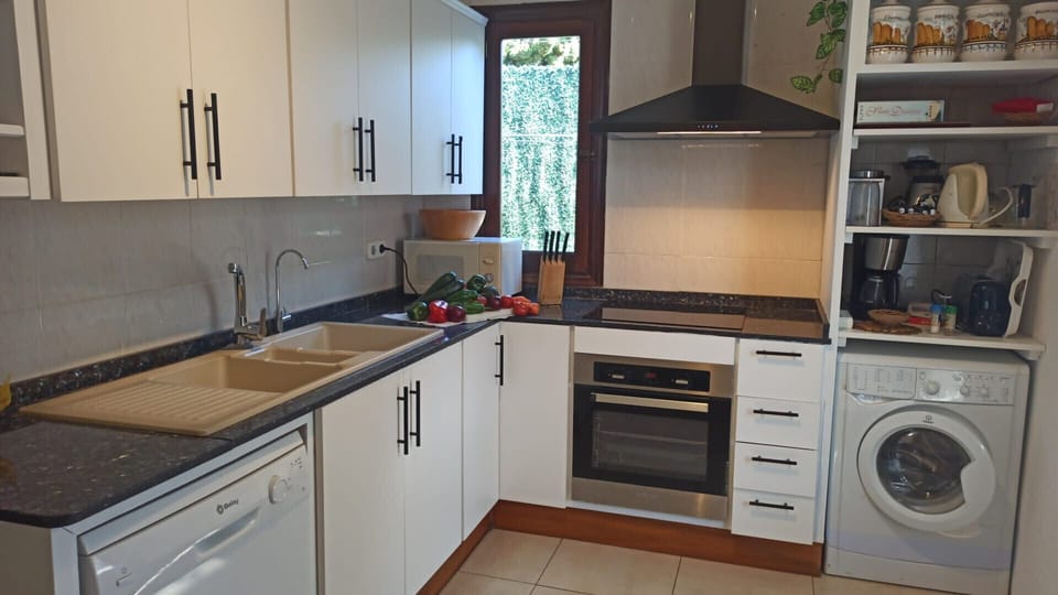 Modern fully equipped kitchen with oven, dishwasher, washing machine, ceramic hob, and ample storage space.