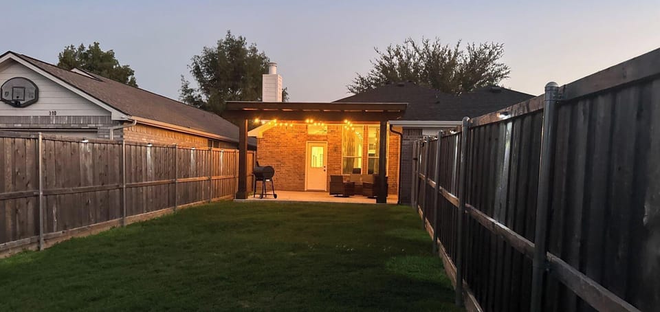 Fenced in backyard with covered patio and a grill