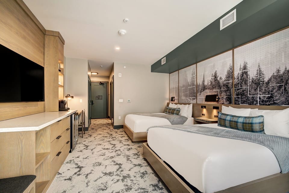 Two queen beds, wall lighting, and a warm alpine palette — four guests, one great base for the mountain