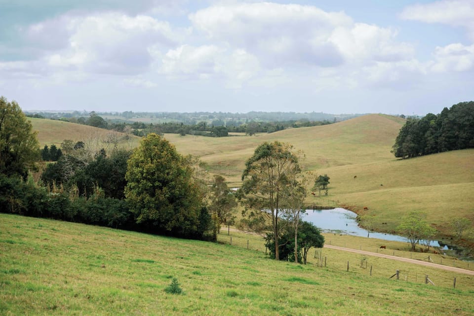 Expansive rural scenery with trees, hills, and tranquil water.