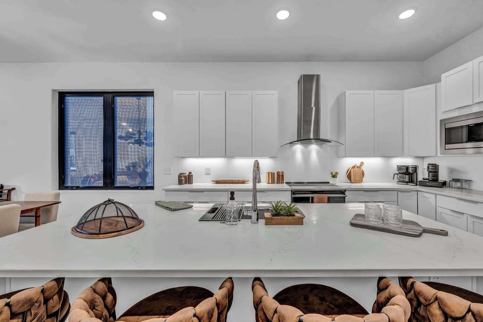A luxurious chef’s kitchen with a grand island, polished finishes, and elegant white cabinetry, designed for both gourmet cooking and stylish entertaining.