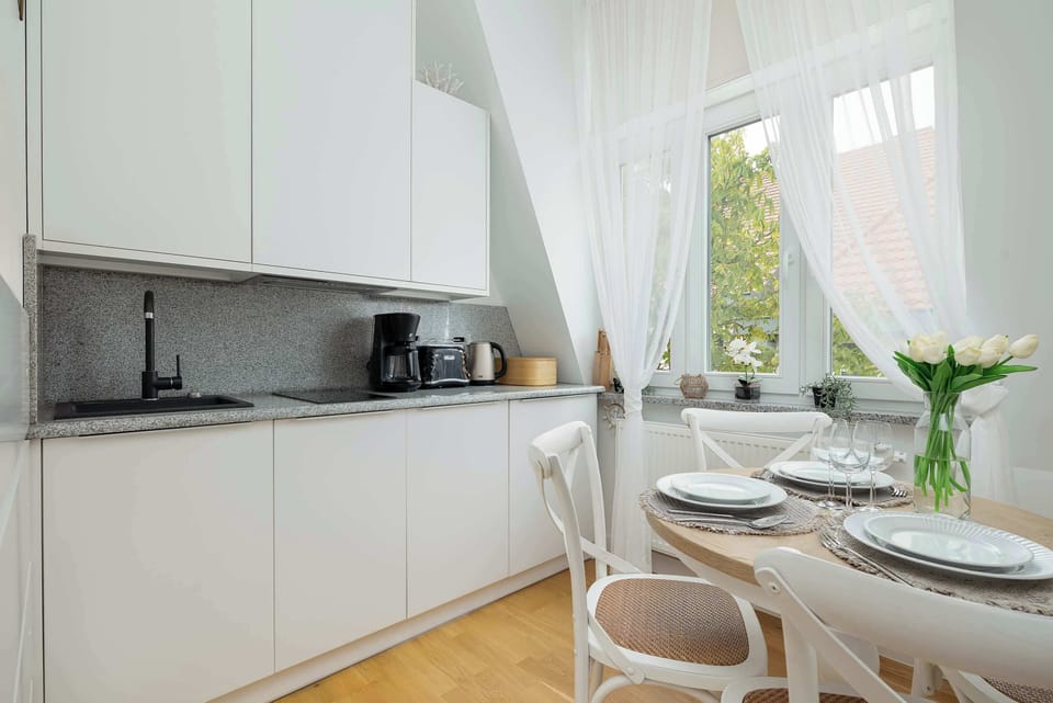 A compact kitchen area with modern appliances. White curtains flow gently by the window.