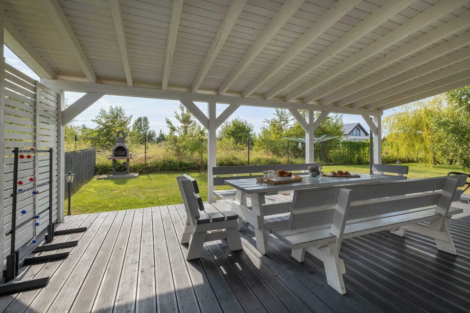 Another outdoor seating area under a roof, featuring wooden benches and a table.
