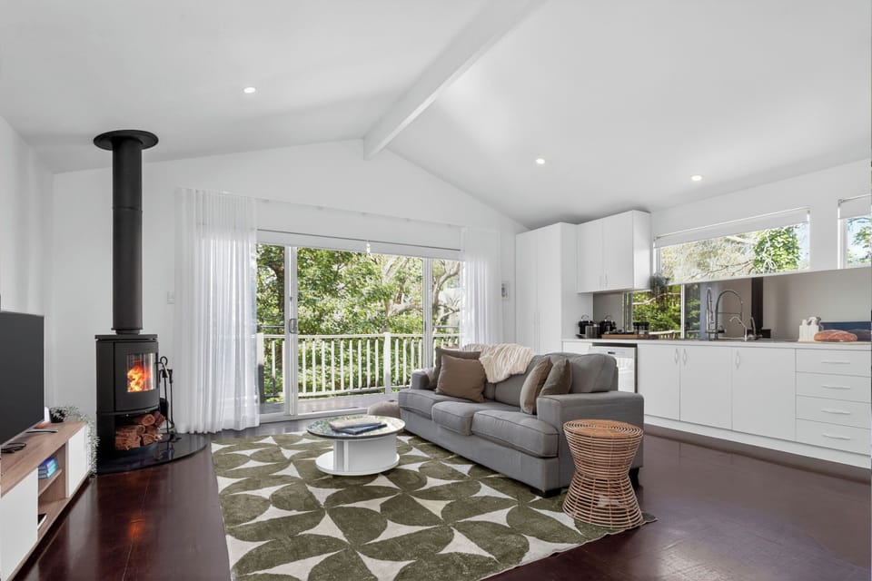 Sunlight fills the upstairs living area, with a cushioned sofa, TV, and fireplace combining to offer a cosy retreat after a day out.