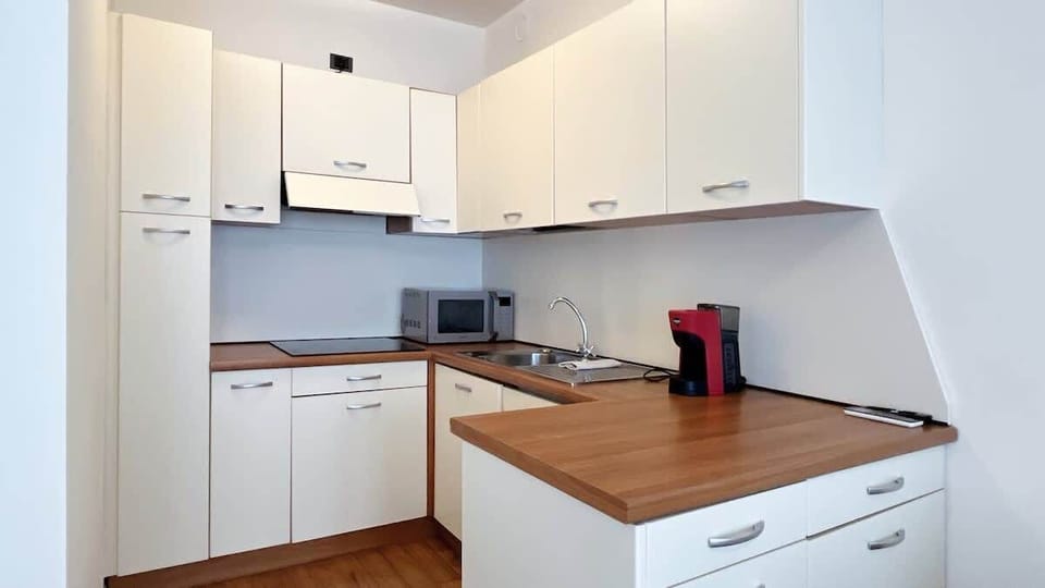 Functional kitchen with a large work surface, coffee machine, microwave and essential appliances.