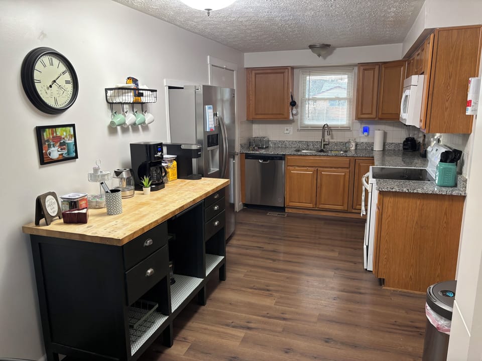 Kitchen with dishwasher is furnished with cookware, toaster, blender, and more.