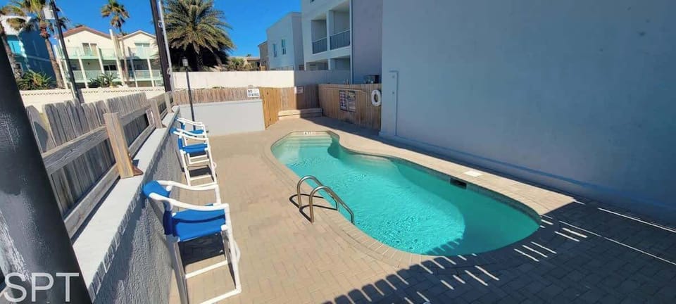 Inviting courtyard pool with turquoise water, sun loungers, and a private, palm‑lined setting — a relaxing outdoor escape perfect for cooling off after a day at the beach.