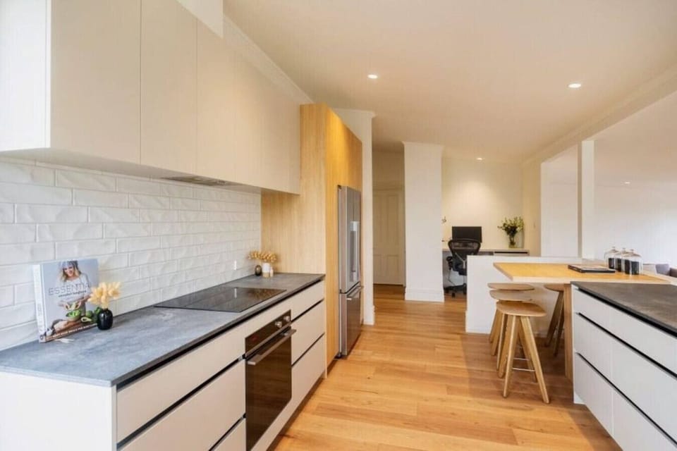 Modern fully equipped kitchen, elevated above the open plan living space, with bar seating, large fridge freezer, oven, stovetop, microwave, waste disposal, Nespresso machine, kettle and toaster