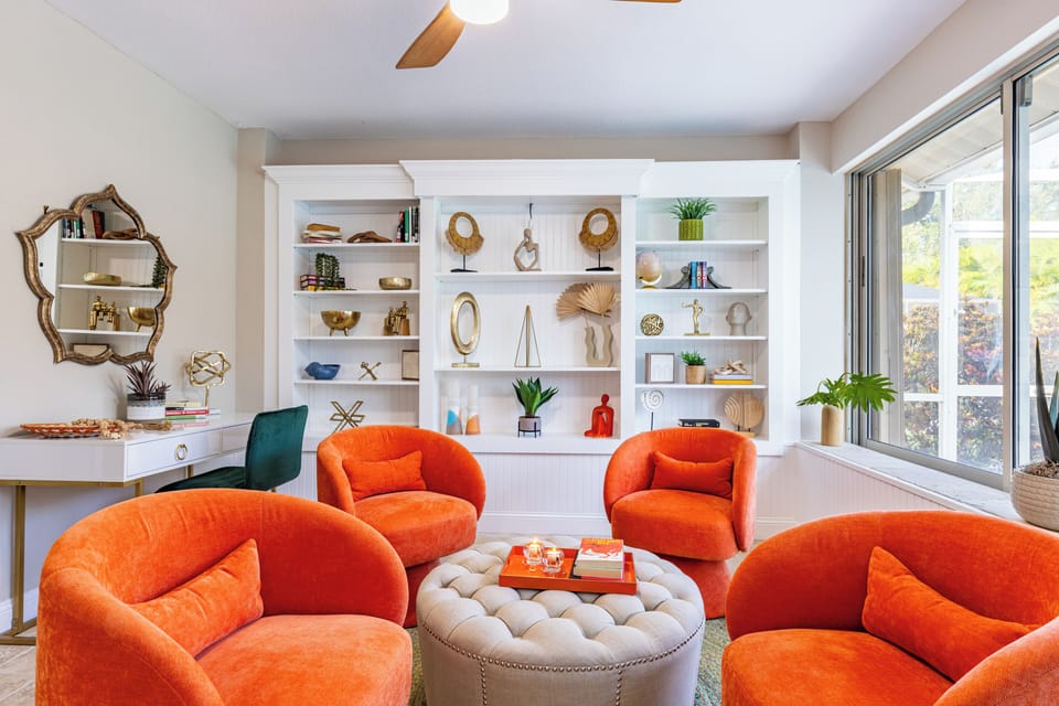 Chic lounge with bold orange chairs and shelving display.