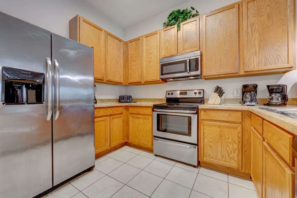 Kitchen with stainless steel appliances and ample oak cabinetry for storage.