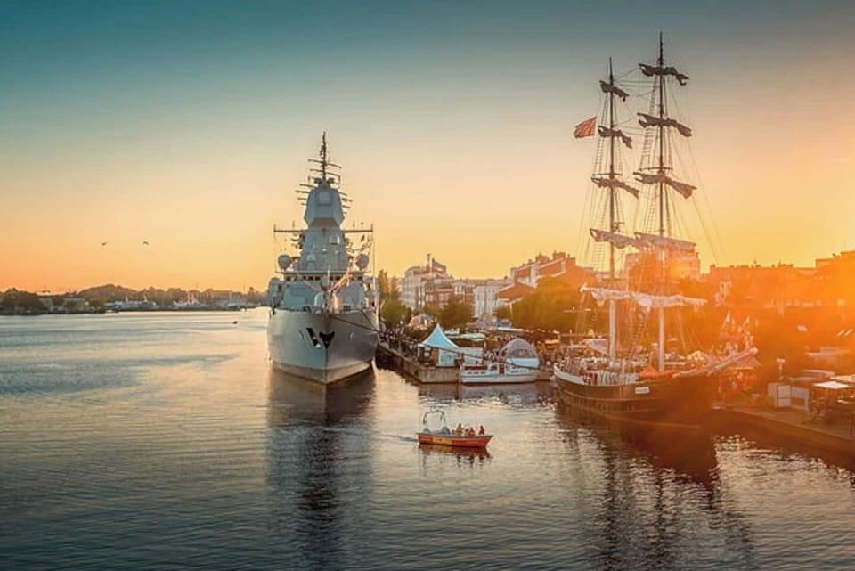 Der malerische Hafen von Wilhelmshaven mit historischen Segelschiffen und moderner Marinekulisse bei Sonnenuntergang zeigt die einzigartige maritime Atmosphäre, die deinen Urlaub an der Nordsee so besonders macht.
