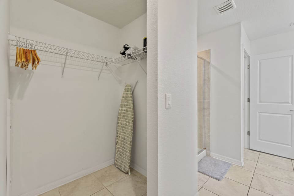 Walk-in closet with ample storage and ironing board – Shine Villas | Sunset Retreat, Storey Lake Resort, Orlando