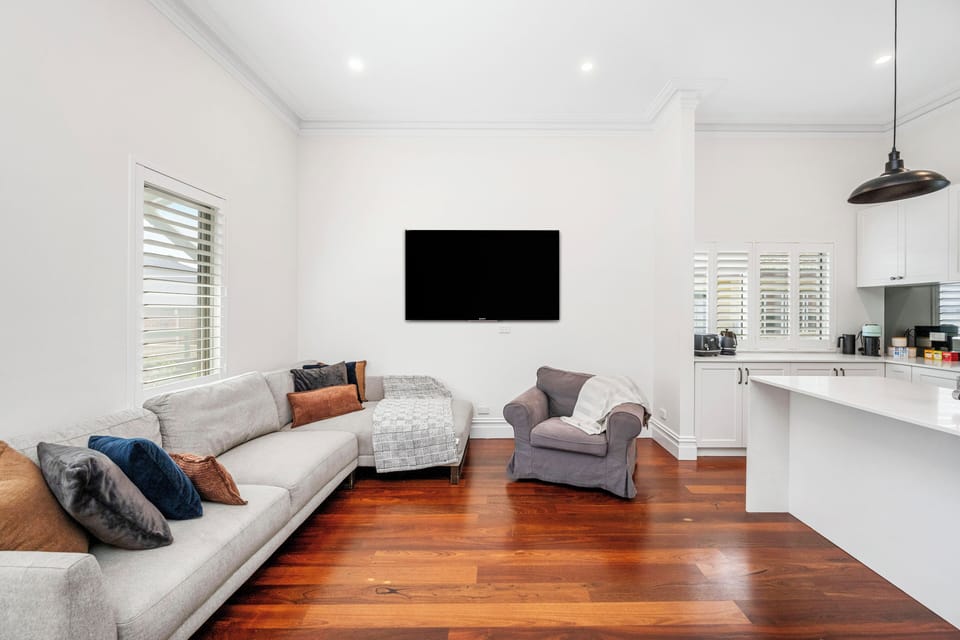 Bright space with wood floors, grey sofa, and TV.