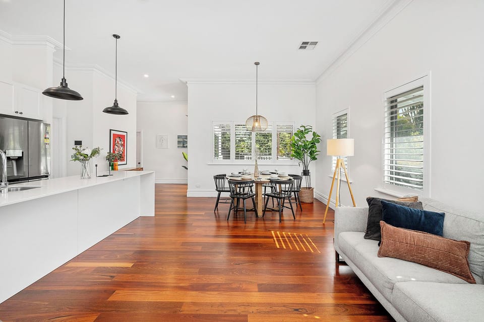 Stylish open-plan living with sofa, dining table, and hardwood floors.