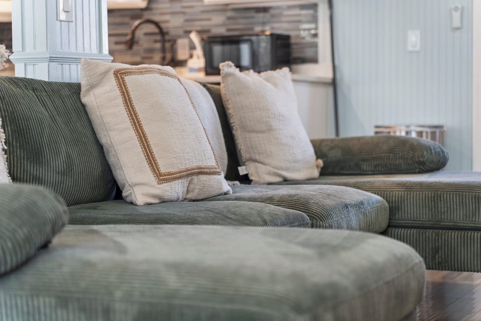 Cozy open living room with TV, books, games, and coastal oyster wallpaper.