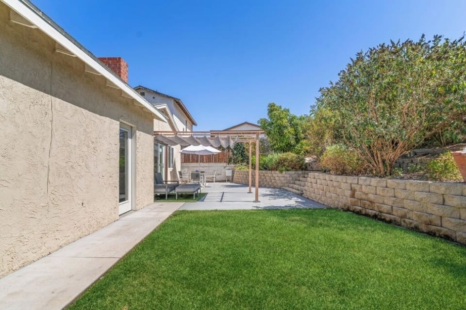 Large outside area, featuring a beige stucco house backdrop